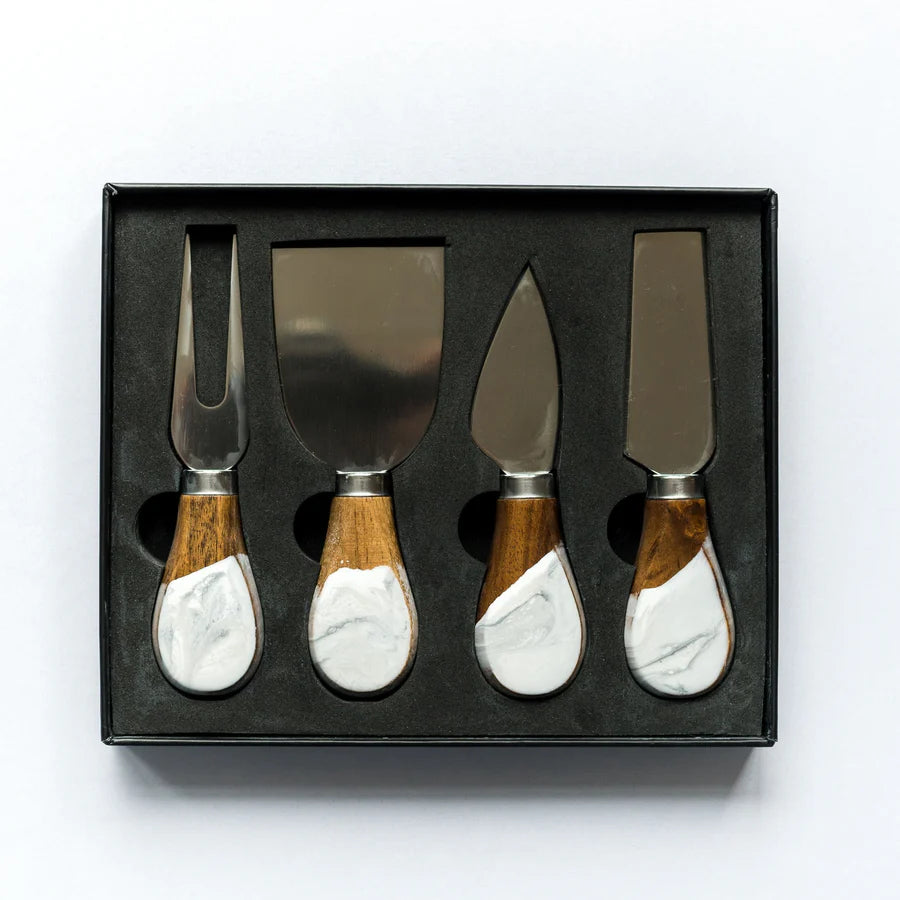 Set of four resin cheese knives with wooden and marble handles in a black box on a white background