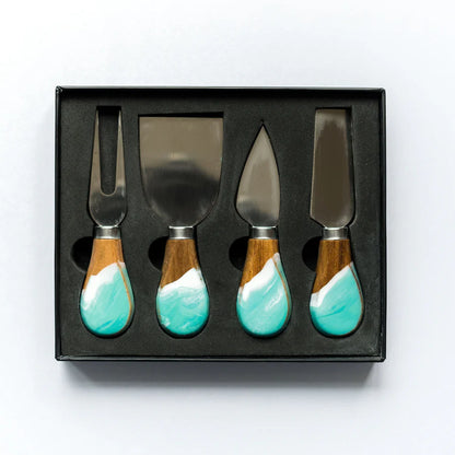 Set of four resin cheese knives with turquoise wooden handles in a black box on a white background