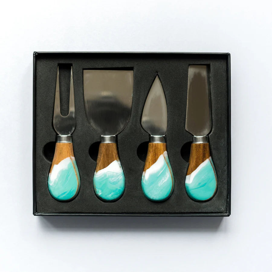 Set of four resin cheese knives with turquoise wooden handles in a black box on a white background