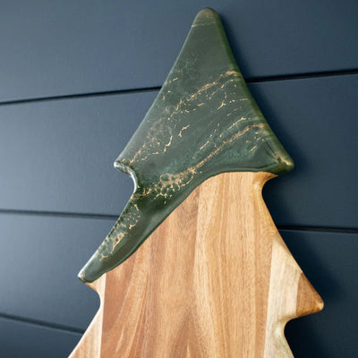 Christmas Tree shaped serving board made of acacia wood with green resin accent, styled with holiday snacks.