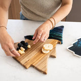Christmas Tree shaped serving board made of acacia wood with green resin accent, styled with holiday snacks.