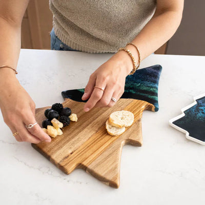 Christmas Tree shaped serving board made of acacia wood with green resin accent, styled with holiday snacks.
