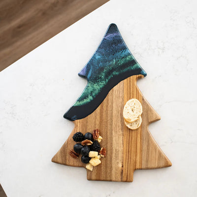 Christmas Tree shaped serving board made of acacia wood with green resin accent, styled with holiday snacks.
