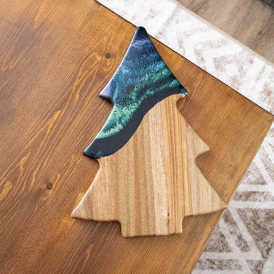Christmas Tree shaped serving board made of acacia wood with green resin accent, styled with holiday snacks.