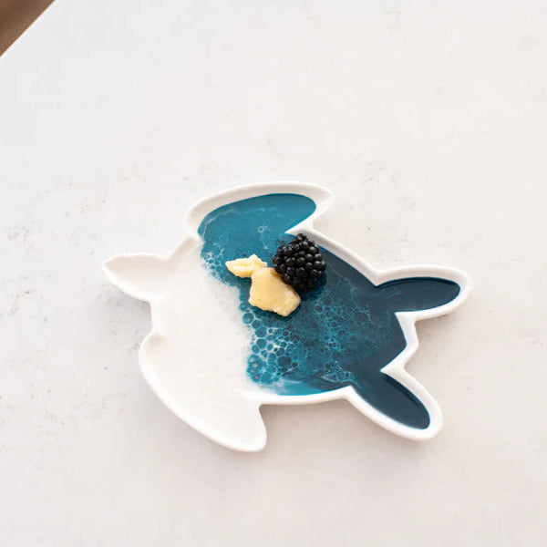 Decorative resin turtle-shaped plate with a black and white object on a light background