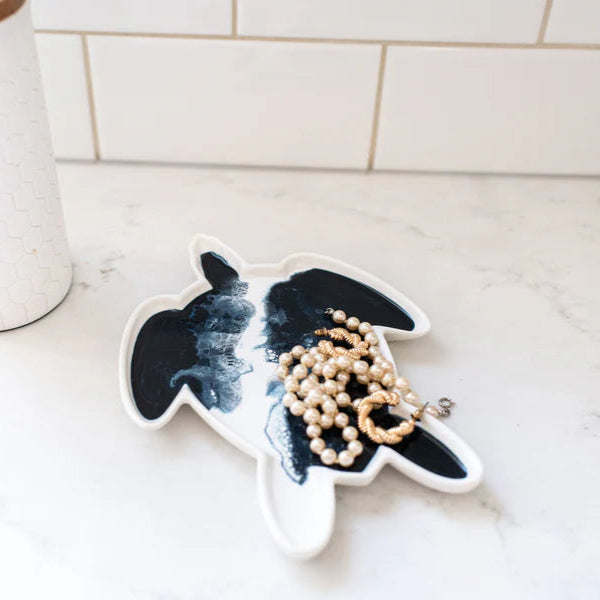 Decorative resin ceramic turtle plate with a necklace on a marble surface