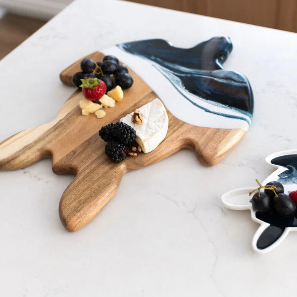 Wooden resin charcuterie board with marble-like design, topped with fruits and cheese, on a white surface.