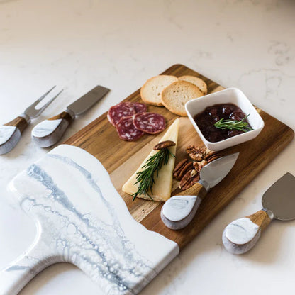 Wooden charcuterie board with sliced meats, cheese, and a small bowl of jam on a marble surface.
