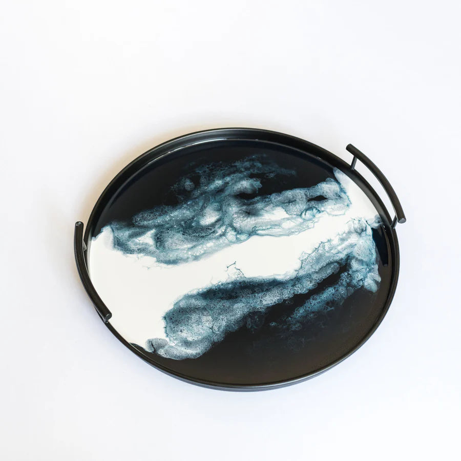 Round black resin tray with abstract white and blue design on a white background