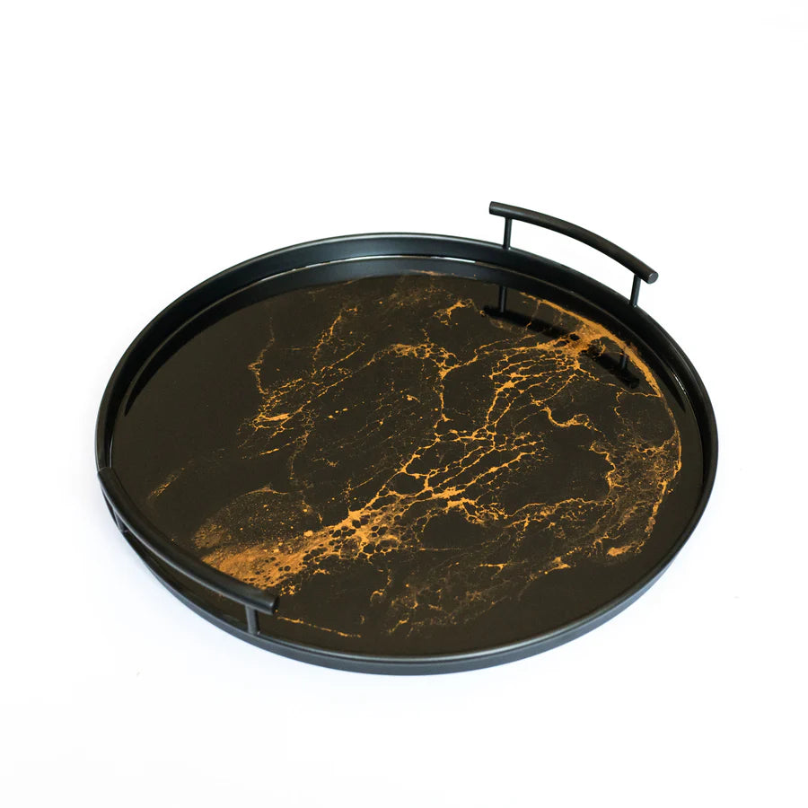 Round resin tray with black and gold marble pattern on a white background