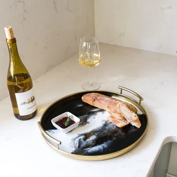 Tray with loaf of bread and sauce on a kitchen counter next to a bottle of wine and glass.