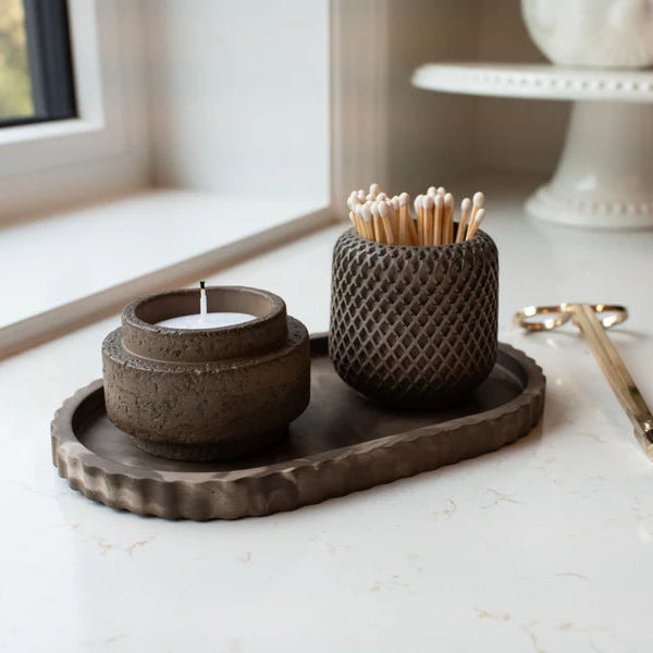 Decorative items including a candle holder, toothpick holder, and tray on a light surface.