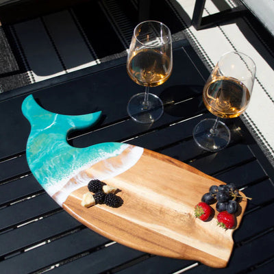 Wooden whale-shaped charcuterie board with ocean-inspired resin design on a white surface
