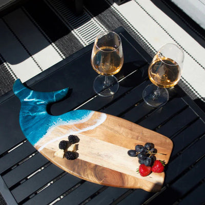Wooden whale-shaped charcuterie board with ocean-inspired resin design on a white surface