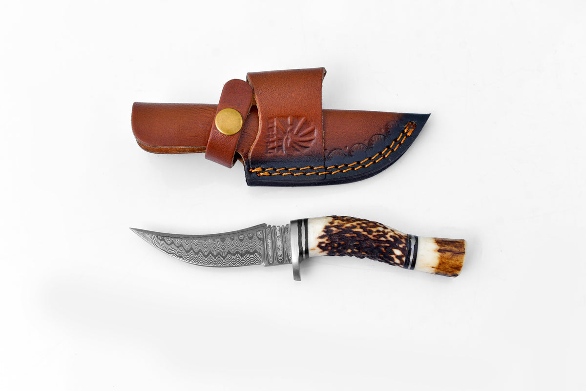 Deer Horn Trailblazer Damascus knife with stag horn handle and leather sheath on wood surface