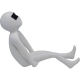 Minimalist white figurine with elongated limbs reclining and wearing black rectangular glasses, shown in profile on white background.