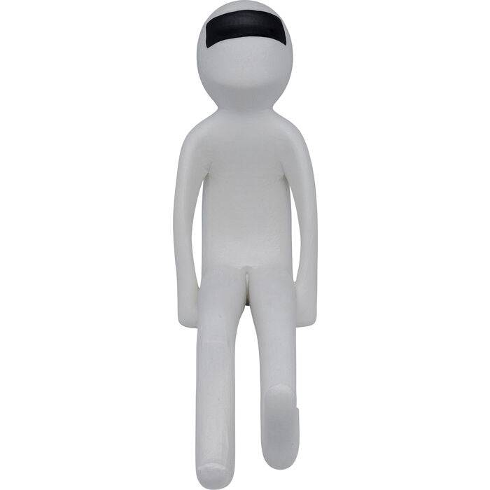 Minimalist white humanoid figurine seated with elongated limbs and a black visor-like band across its face against a plain background.