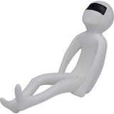 Minimalist white figurine with a smooth surface sitting with legs extended and arms relaxed, featuring a black band covering its eyes.