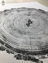 Black ink print of a tree cross-section showing detailed annual rings and textured bark edges on white paper, angled for a three-dimensional view.