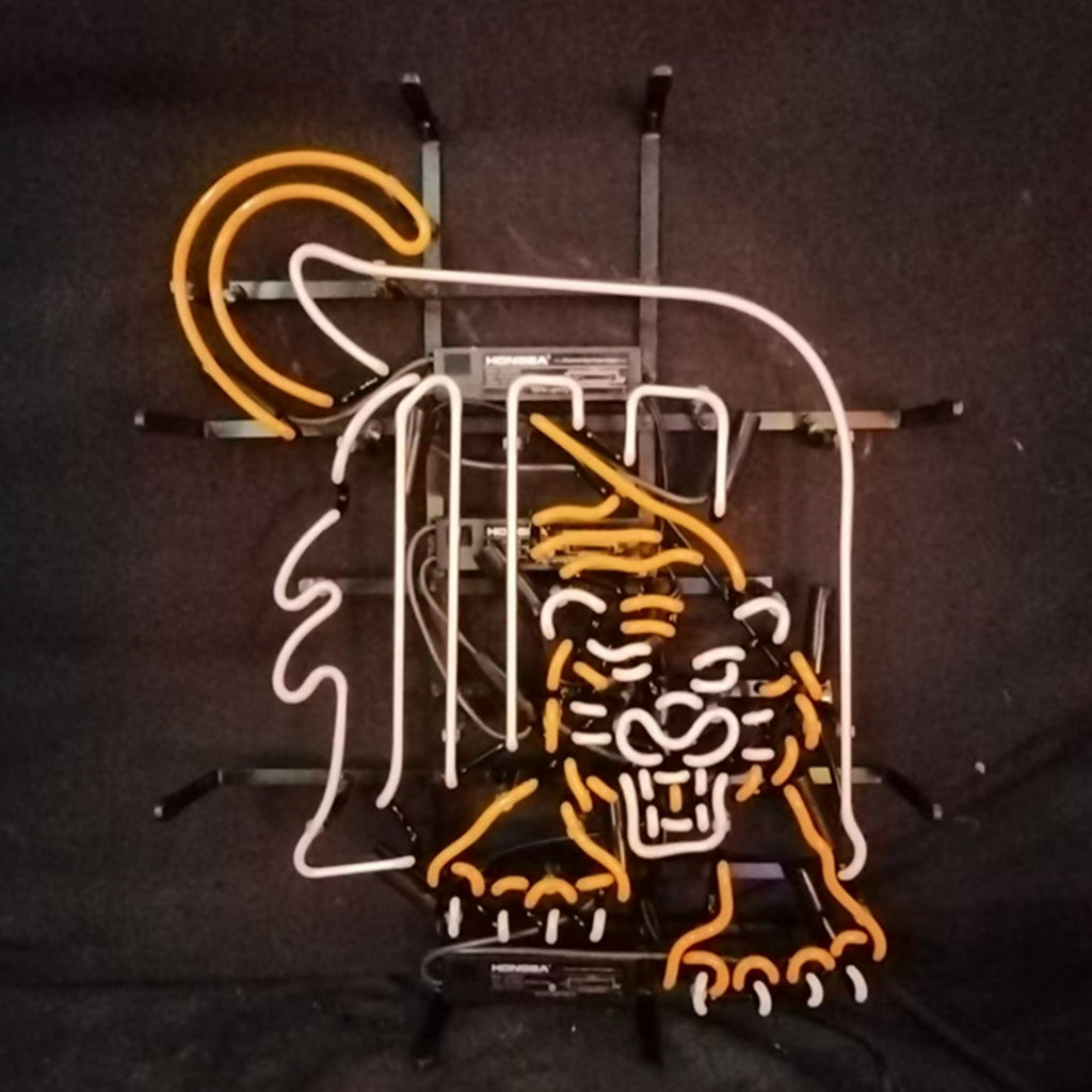Orange and white neon sign depicting a crouching tiger with a bold outline and a circular element behind it, mounted on a black background frame.