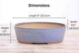 Oval bonsai pot in denim blue glaze with subtle texture, measuring 8 inches long, 6.5 inches wide, and 2.5 inches high, shown from the side on a wooden surface.
