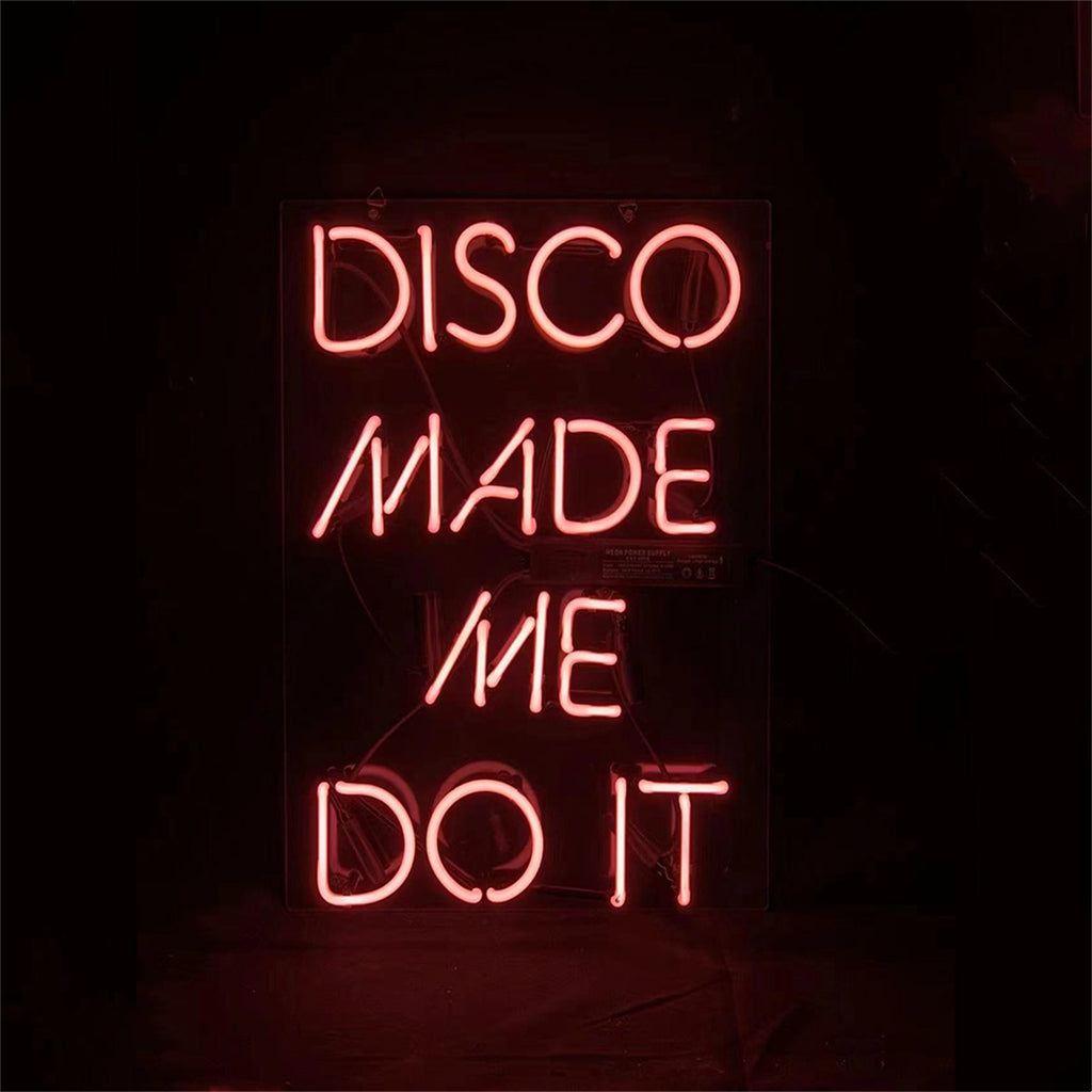 Vertical pink neon sign on black background reading 'DISCO MADE ME DO IT' in a simple sans-serif style.