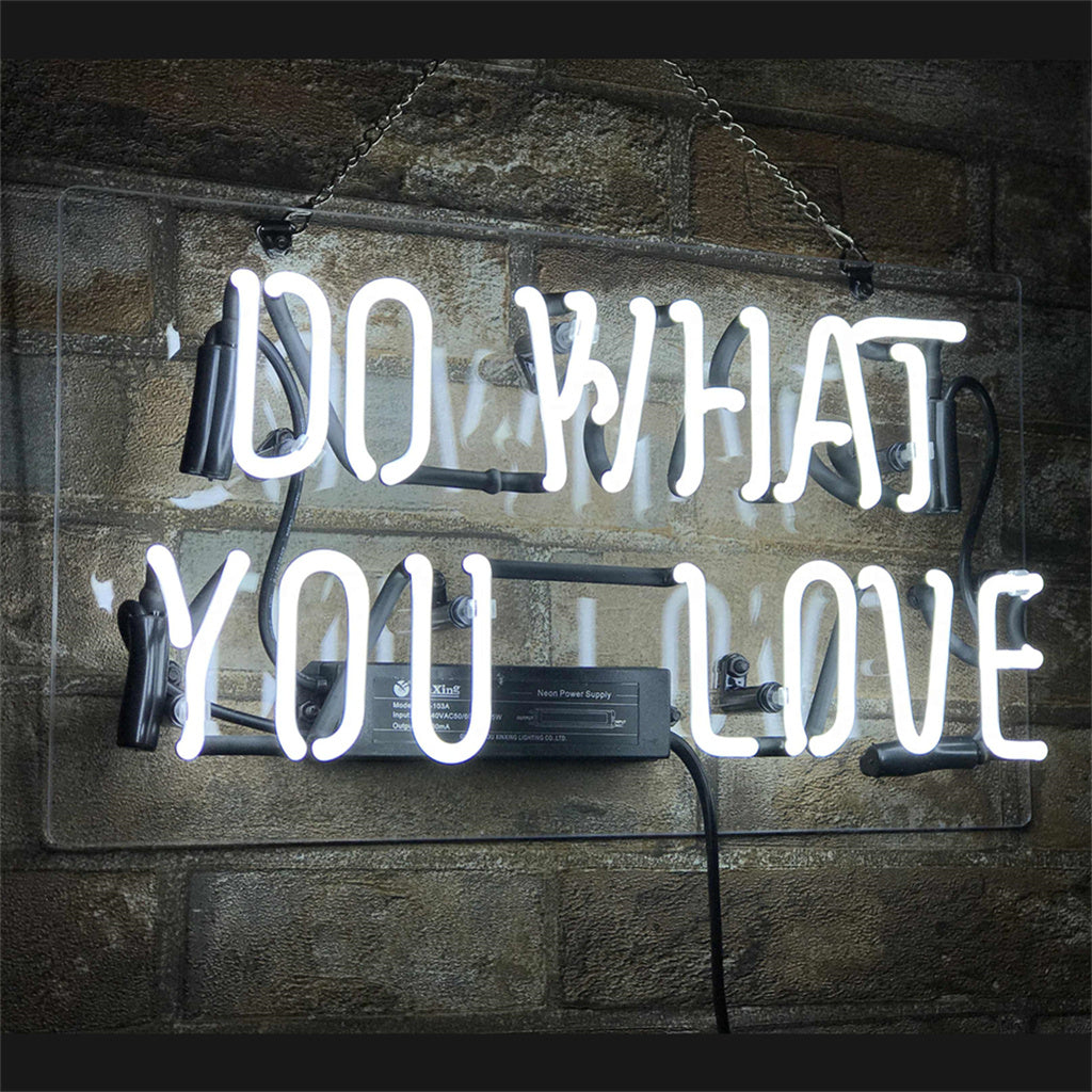 White neon sign saying 'DO WHAT YOU LOVE' mounted on a transparent panel against a textured brick wall, with visible black power cords and fixtures.
