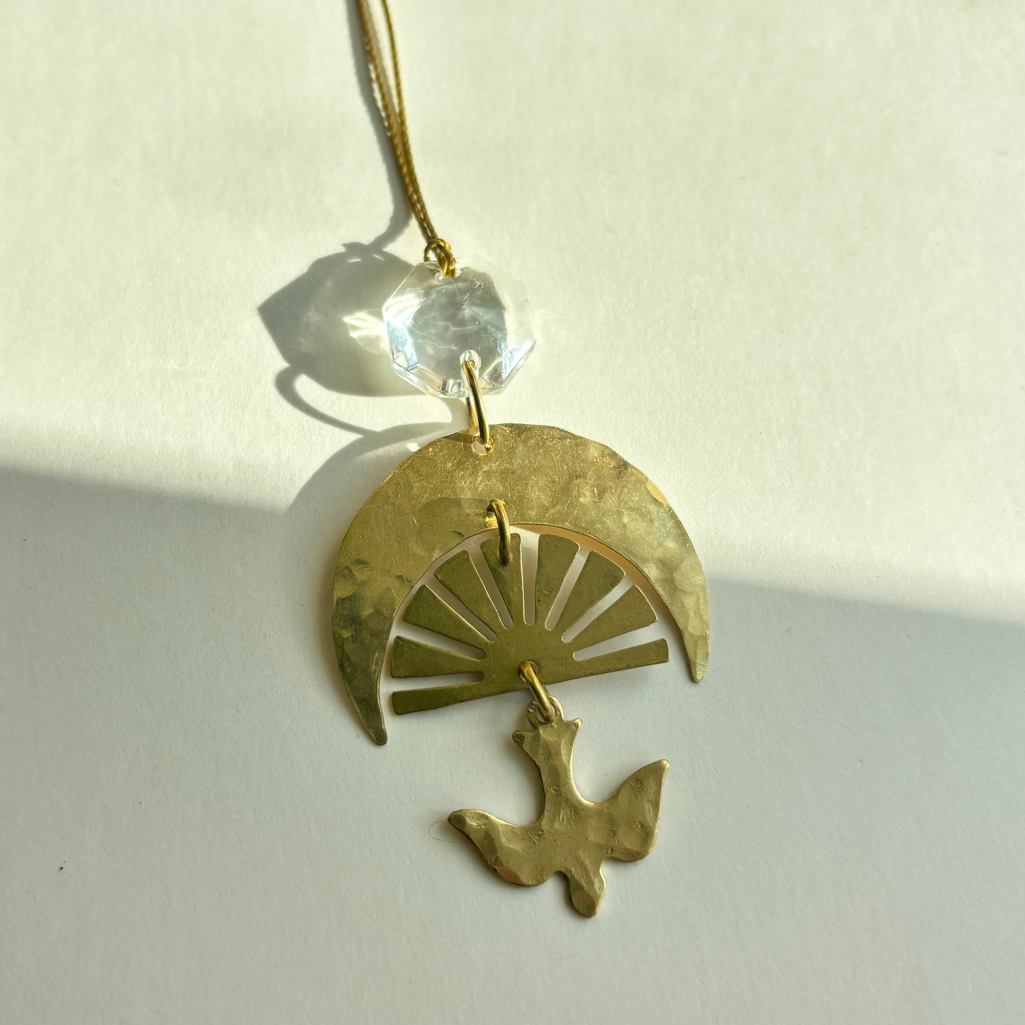Chasing Light Ornament with hand-cut brass and vintage glass crystal hanging against white background