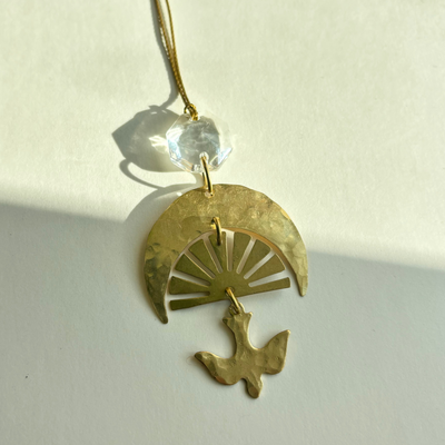 Chasing Light Ornament with hand-cut brass and vintage glass crystal hanging against white background