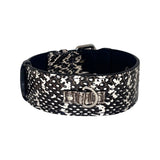 Black and white snake-patterned dog collar with a silver D-ring and buckle, shown in a circular shape on a white background.