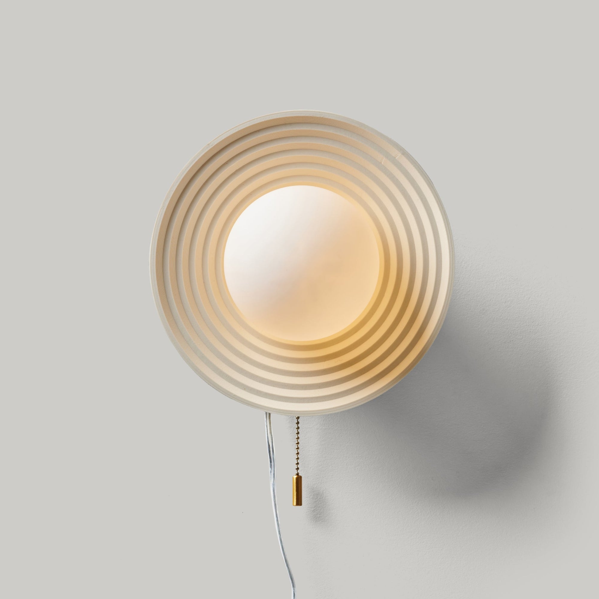 Echo Sconce lamp in eggshell finish mounted on a wall with concentric circle design.