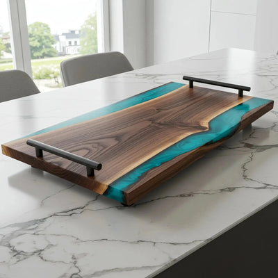 Live edge black walnut charcuterie board with deep teal epoxy river and matte black handles, polished finish