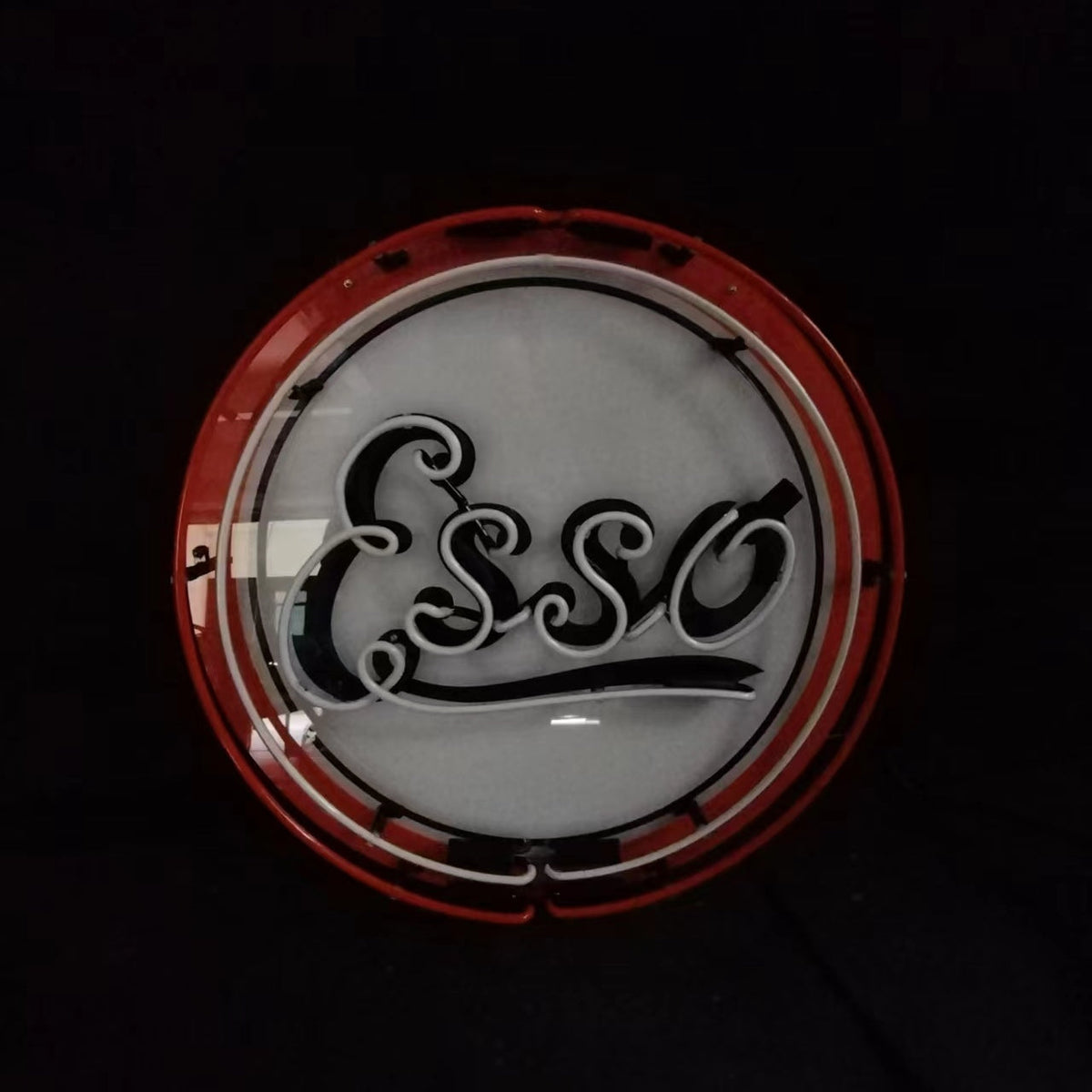 Round neon sign featuring the word 'Esso' in black cursive script on a white background with a red circular border.