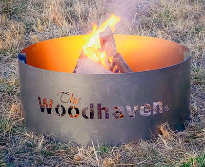 Woodhaven Portable Steel Fire Pit with stainless steel cooking grate, shown outdoors