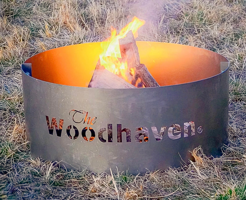 Woodhaven Portable Steel Fire Pit with stainless steel cooking grate, shown outdoors