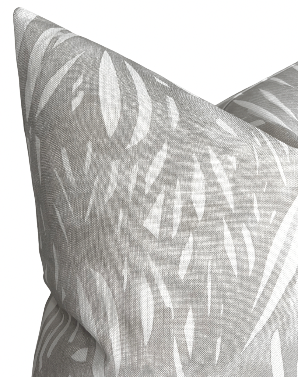 Close-up of a grey pillow cover featuring an abstract white pattern resembling elongated leaf shapes on a textured fabric surface.