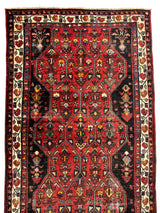 Vintage Persian Hosseinabad rug with a rich red field, intricate geometric medallions, and a contrasting cream border featuring floral motifs.