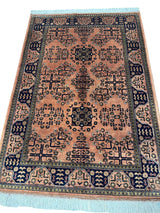 Rectangular hand-knotted Bukharayi rug featuring intricate navy and black geometric motifs on a peach background with a detailed navy and peach border and pale blue fringe ends.
