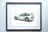 Framed 5x7 watercolor print of a silver BMW Z3 M Coupe viewed from the side and rear, with a faint fence background, on a white wall.