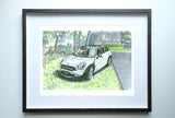 Framed watercolor painting of a white Mini Cooper Countryman parked on a grassy lawn beside a driveway with trees and a house in the background.