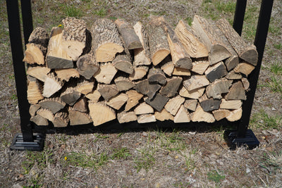 Black and brown firewood rack support bases stacked on concrete and grass surfaces