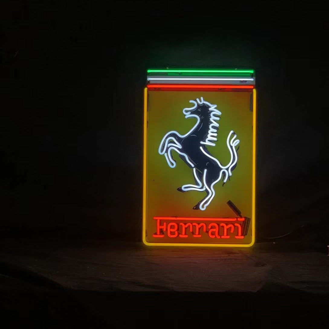 Neon sign featuring a prancing white horse outlined in blue on a yellow rectangle with red neon 'Ferrari' text below and green, white, and red stripes above it against a black background.