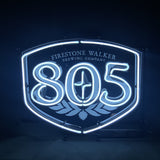 White neon sign shaped like a shield with 'Firestone Walker Brewing Company' text above and large '805' numbers centered, glowing against a dark background.