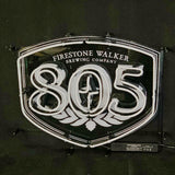 White neon sign shaped like a shield displaying 'Firestone Walker Brewing Company' above large numbers '805' with a hop flower design underneath on a dark background.