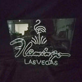 Neon sign with a flamingo design above the cursive word 'Flamingo' and block letters spelling 'LAS VEGAS' on a dark reflective background.