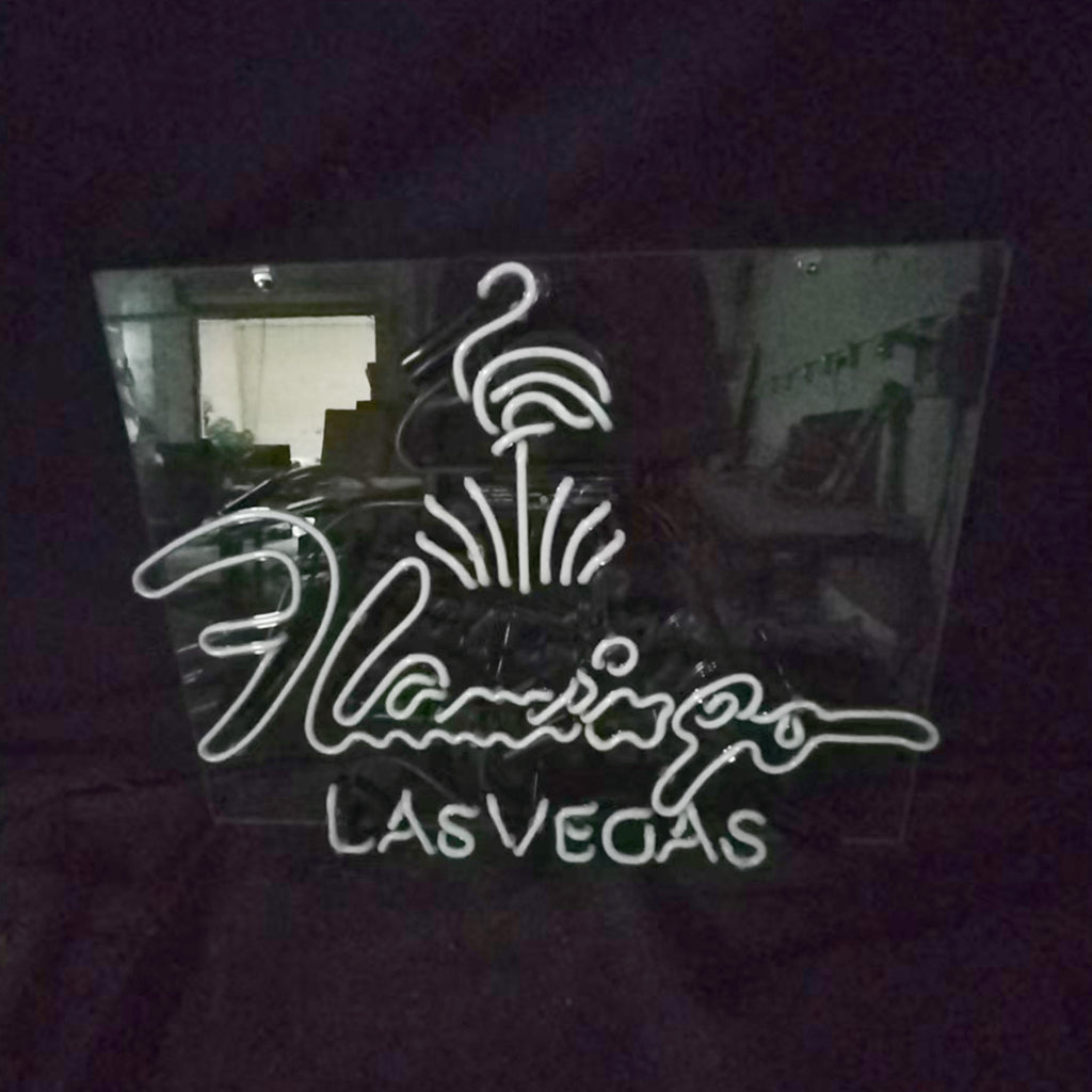 Neon sign with a flamingo design above the cursive word 'Flamingo' and block letters spelling 'LAS VEGAS' on a dark reflective background.