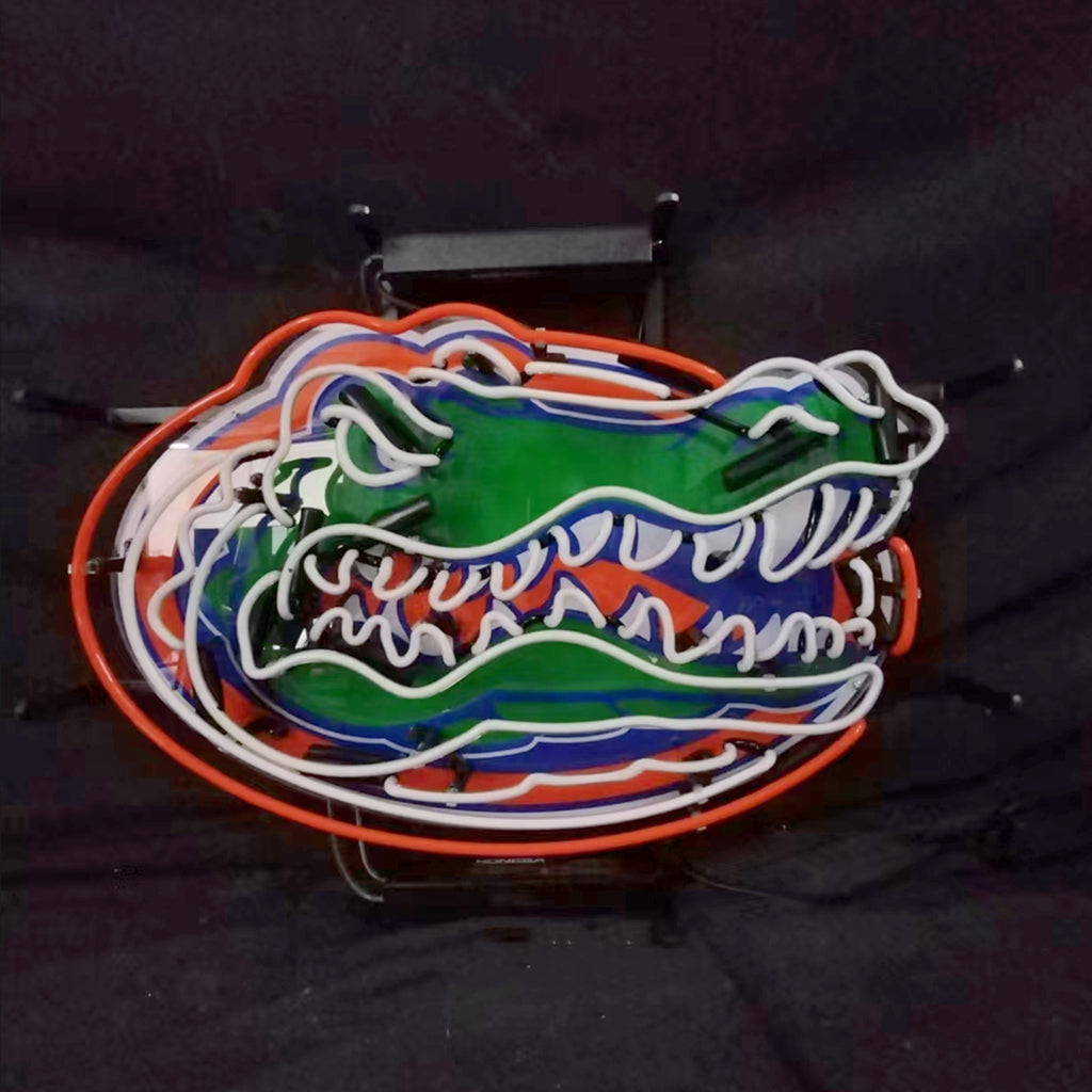Neon sign shaped like a green alligator head with white teeth, orange and blue accents on a black background