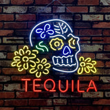 Neon sign of a white skull with yellow flower eyes and a blue nose, surrounded by yellow flowers and green leaves, with red text 'TEQUILA' below, on a brick wall.