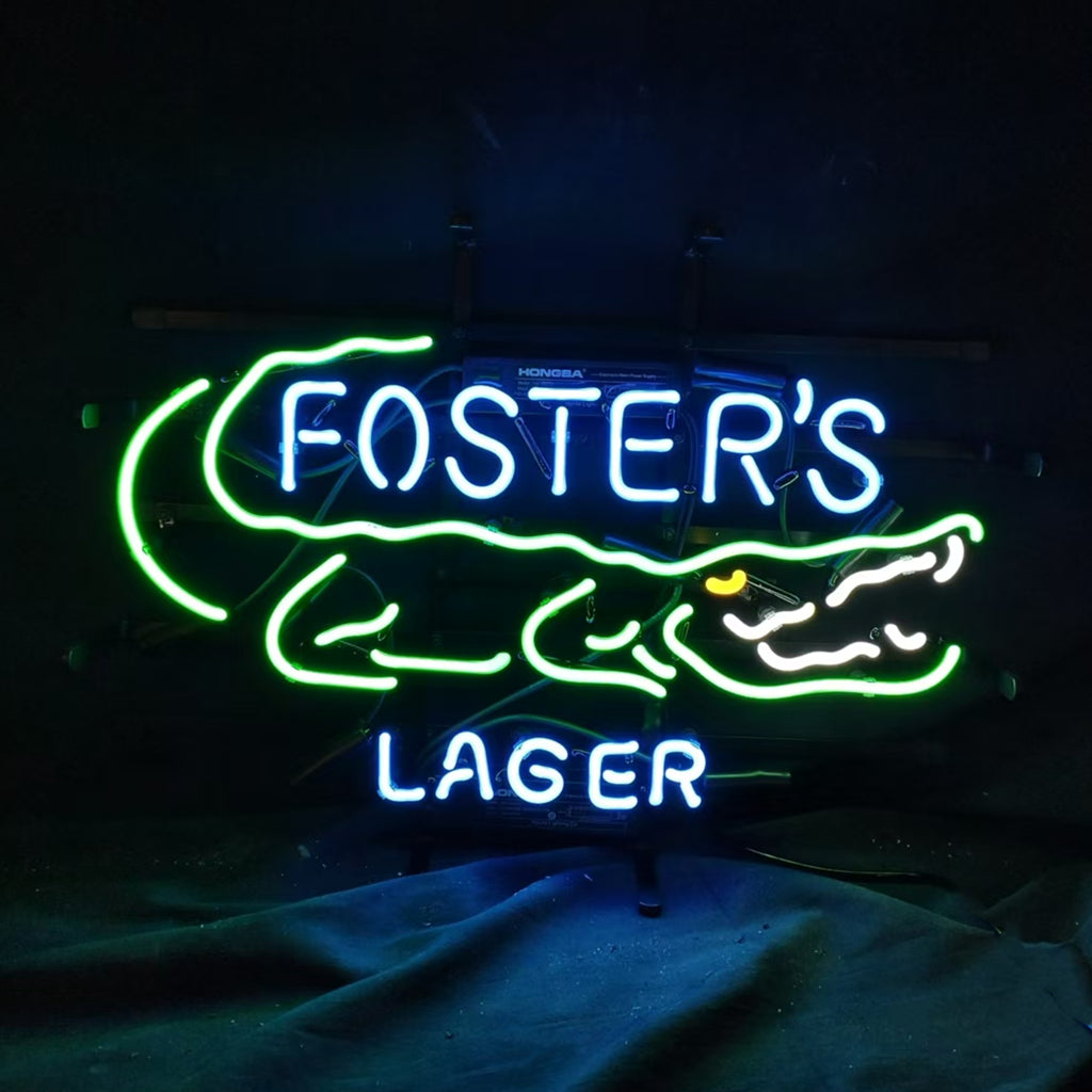 Neon sign depicting a green alligator outline with yellow eye and white teeth, with 'FOSTER'S' in blue neon above and 'LAGER' below