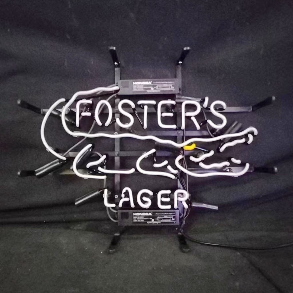 White neon sign depicting a stylized alligator outline with 'FOSTER'S' inside and 'LAGER' below on a black metal frame against a dark background.